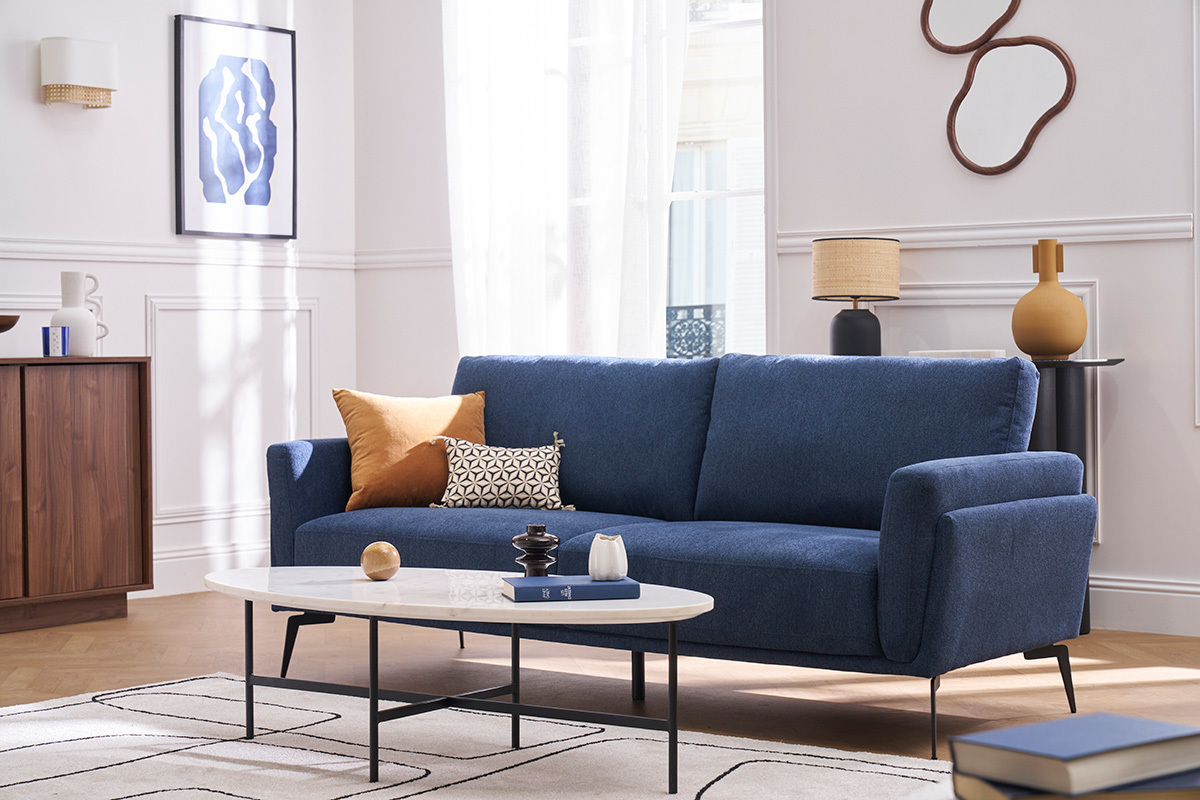 3-Sitzer-Designsofa aus blauem strukturiertem Stoff mit dekorativen Kissen, Gesamtansicht in einem Wohnzimmer.