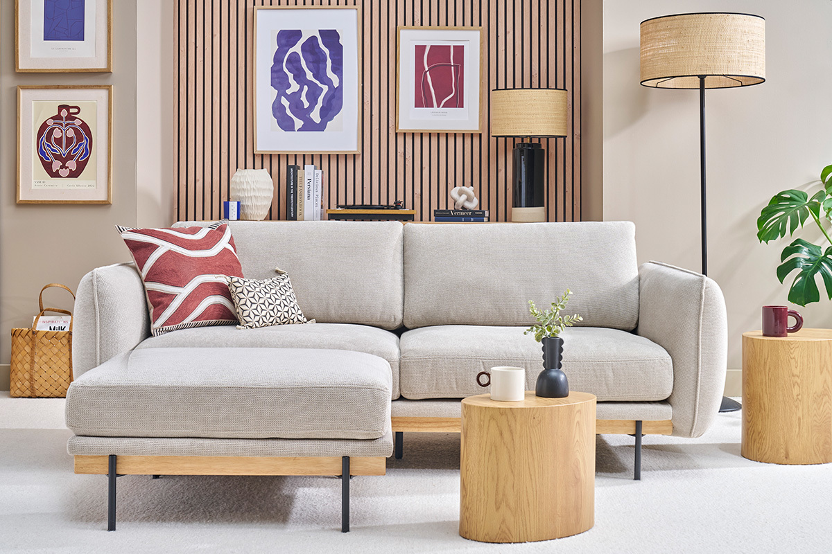 Beiges 3-Sitzer Sofa mit Fu�st�tze, frontalwinklig, umgeben von Holztischen und moderner Wanddekoration.