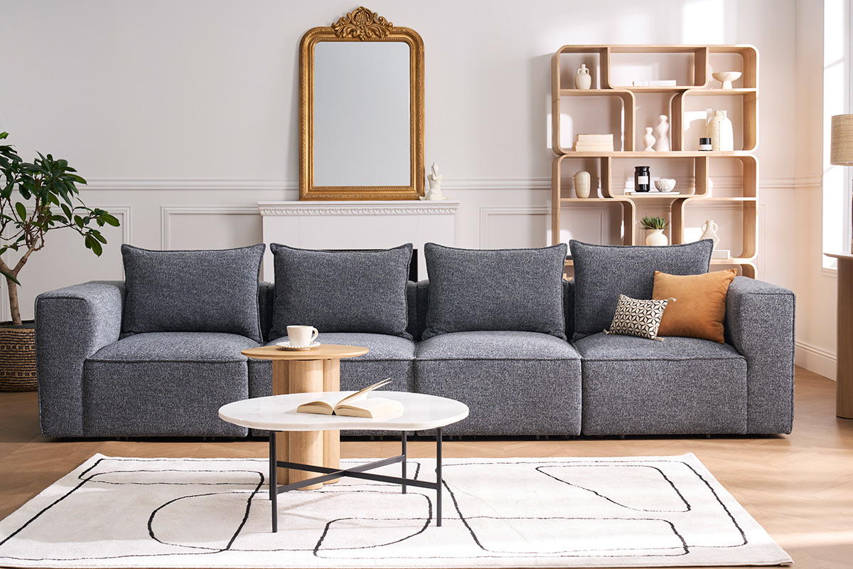 Modulares 5-Sitzer-Sofa aus grauem Stoff, Frontansicht, mit Couchtisch und Dekoration.