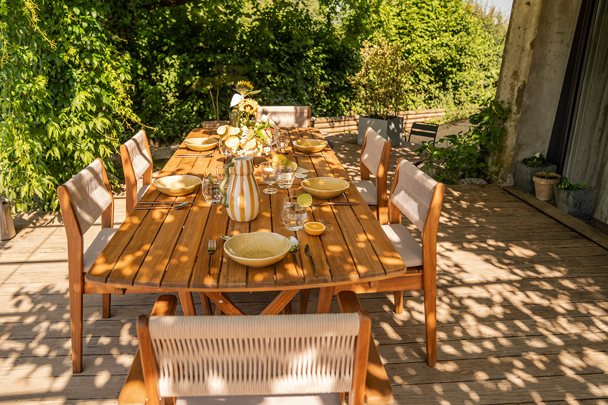 Ausziehbarer Gartentisch aus Massivholz, Seitenansicht mit Geschirr, bereit f�r eine Mahlzeit im Freien.