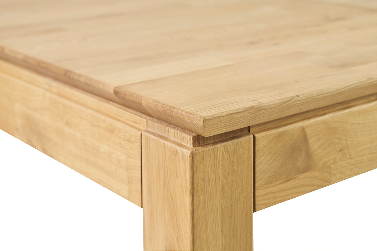 Detail einer Ecke eines hellen Holzesstammtisches, Tischplatte und Bein sichtbar.