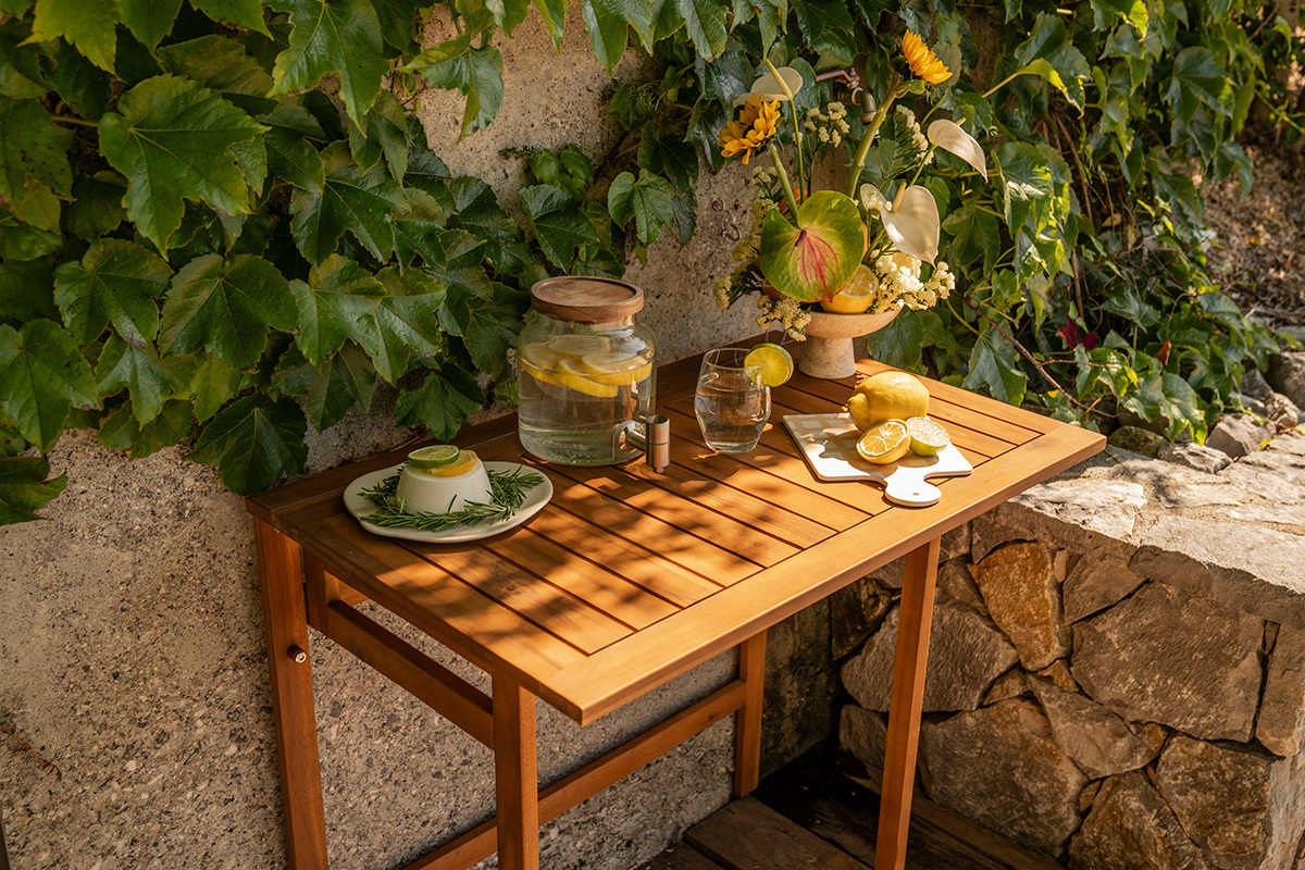 Klapptisch f�r den Balkon aus Massivholz mit Dekorationen, Draufsicht, umgeben von Pflanzen.