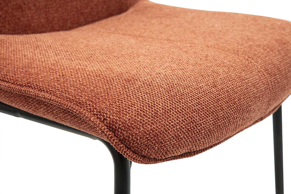 Nahaufnahme eines Hockers mit Stoffbezug in gebrannter Erde und schwarzem Metallgestell.