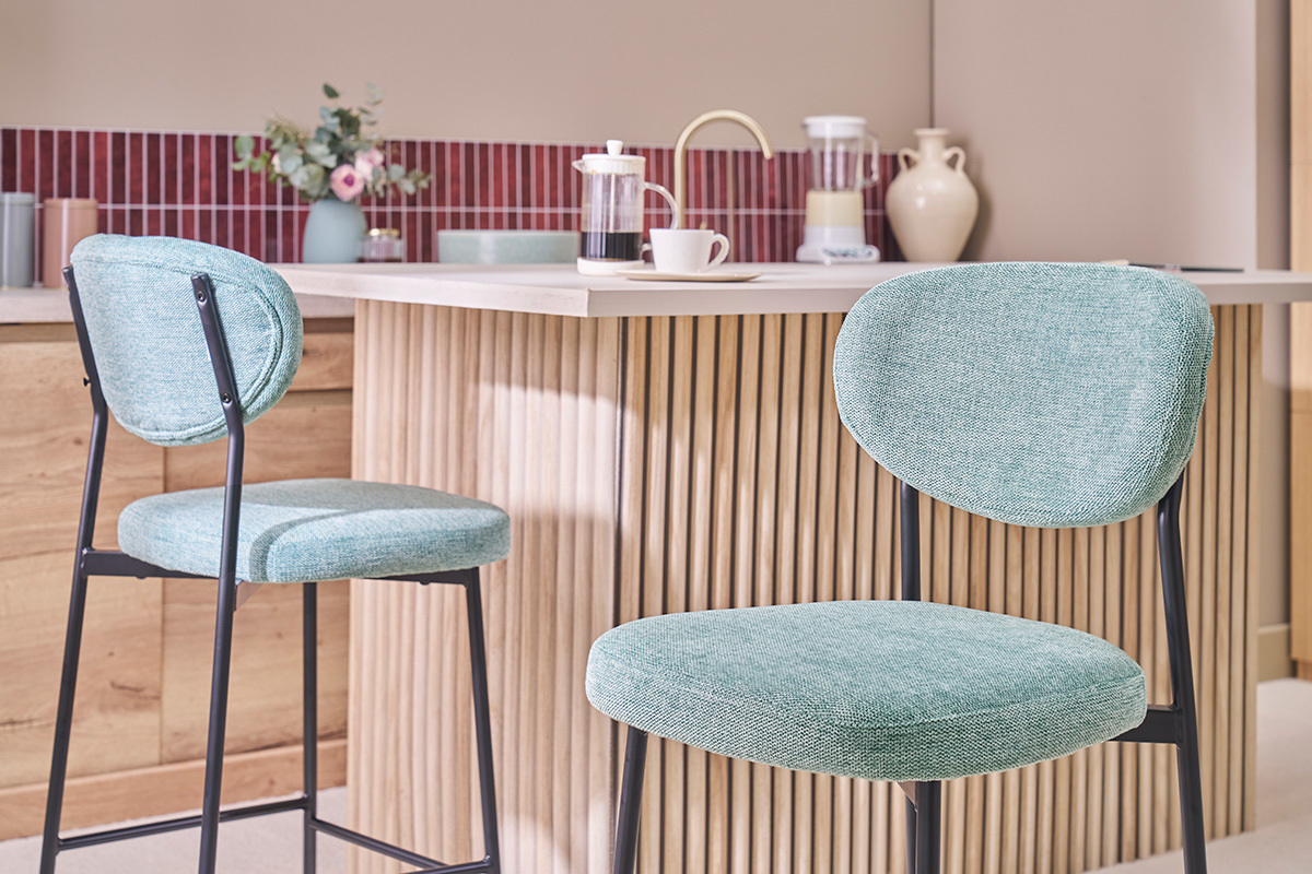 Zwei Barhocker aus Z�ladon-Stoff und schwarzem Metall vor einer K�cheninsel.