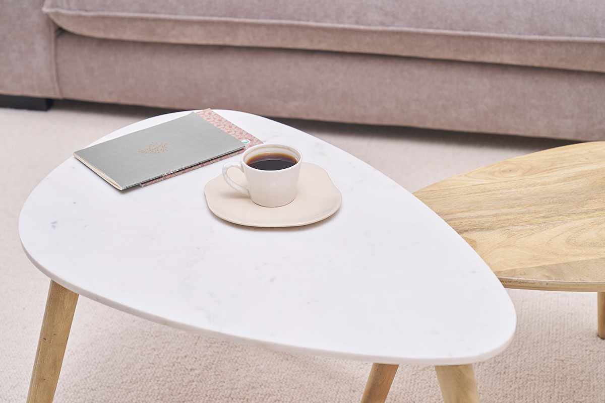 Niedrige ineinander passende Tische aus Marmor und Holz, mit Tasse und Notizbuch.