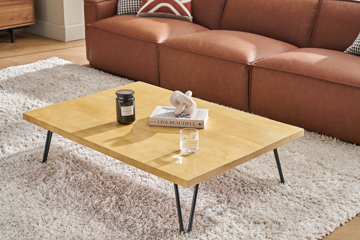 Rechteckiger Couchtisch aus Mangoholz mit schwarzen Metallbeinen, Ansicht von der Seite, auf weiem Teppich.