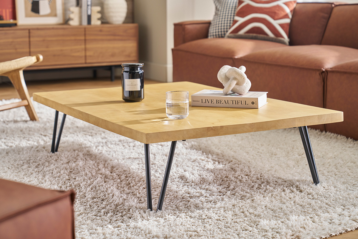 Rechteckiger Couchtisch aus Mangoholz auf einem Teppich, Seitenansicht mit Dekorationsobjekten.