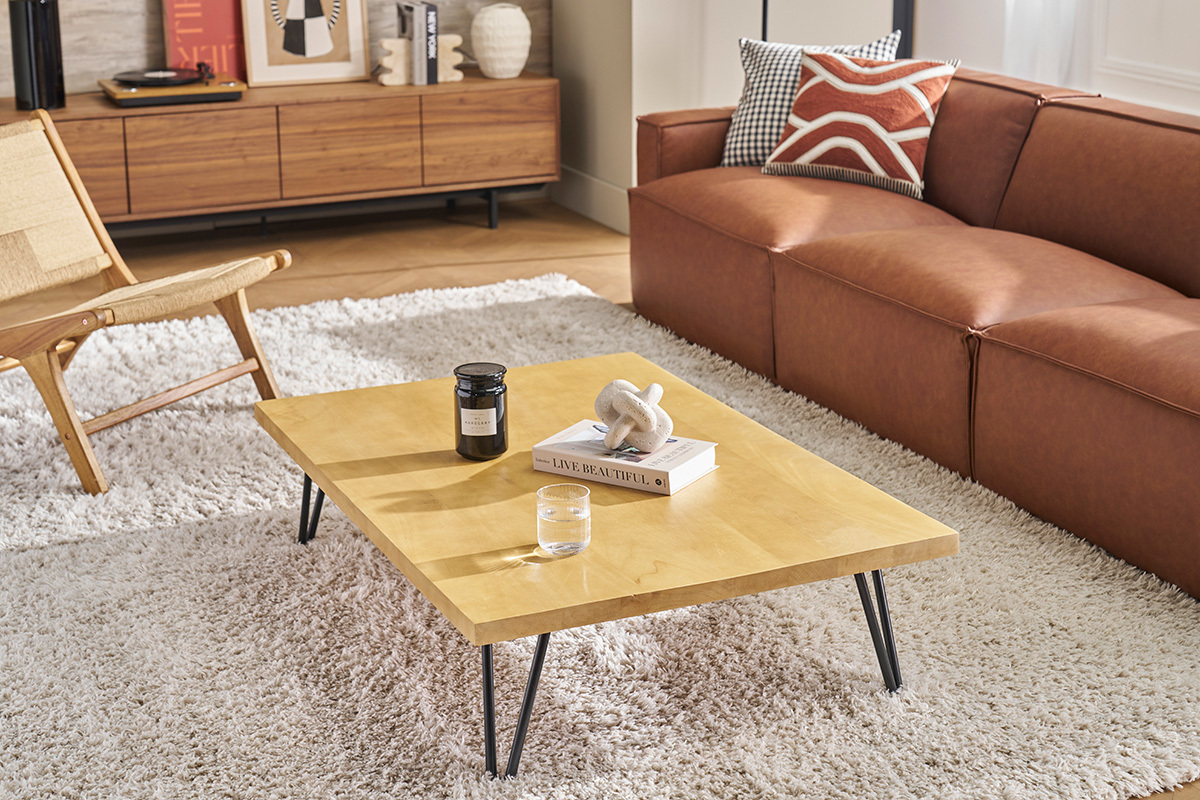 Niedriger Tisch VIBES aus Mangoholz und Metall, Dreiviertelansicht, in einem Wohnzimmer mit Sofa und Sessel.