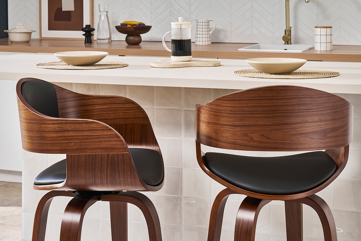 Zwei dunkle Holz- und schwarze Barhocker, Design, vor einer K�chenbar platziert.