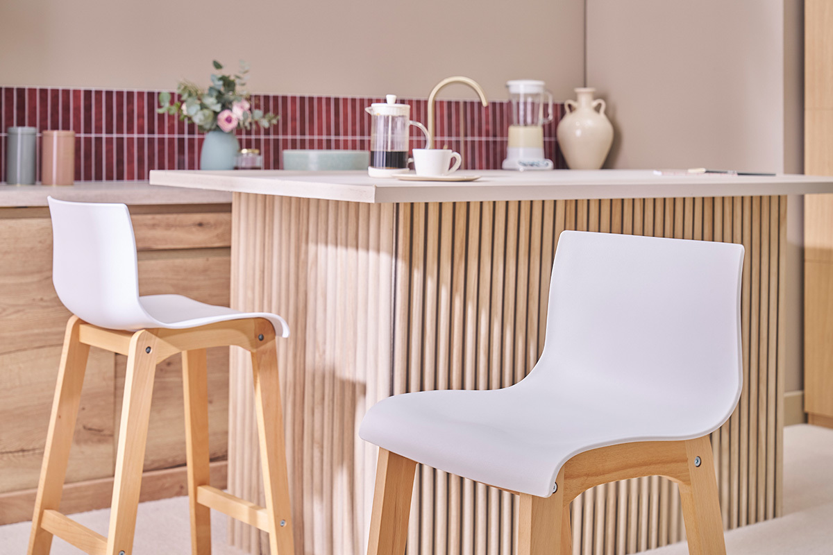 Design-Barhocker aus Holz und Wei� H65 cm vor einer K�cheninsel.