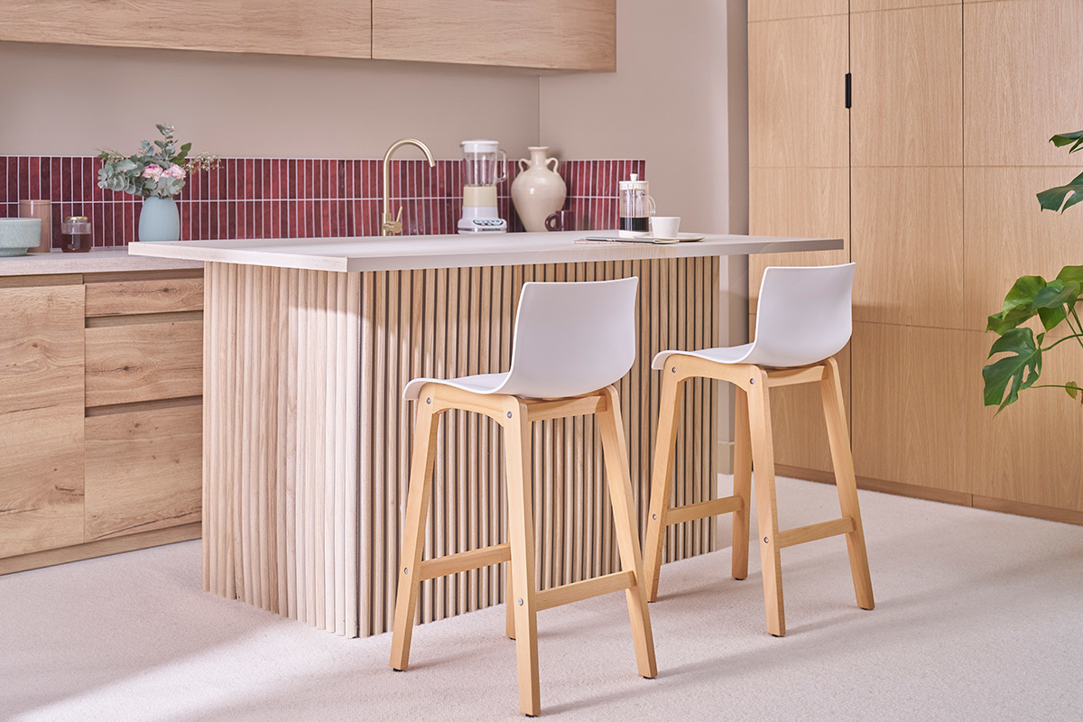 Zwei Holz- und Wei�-Barhocker mit R�ckenlehne, vor einer K�cheninsel platziert.