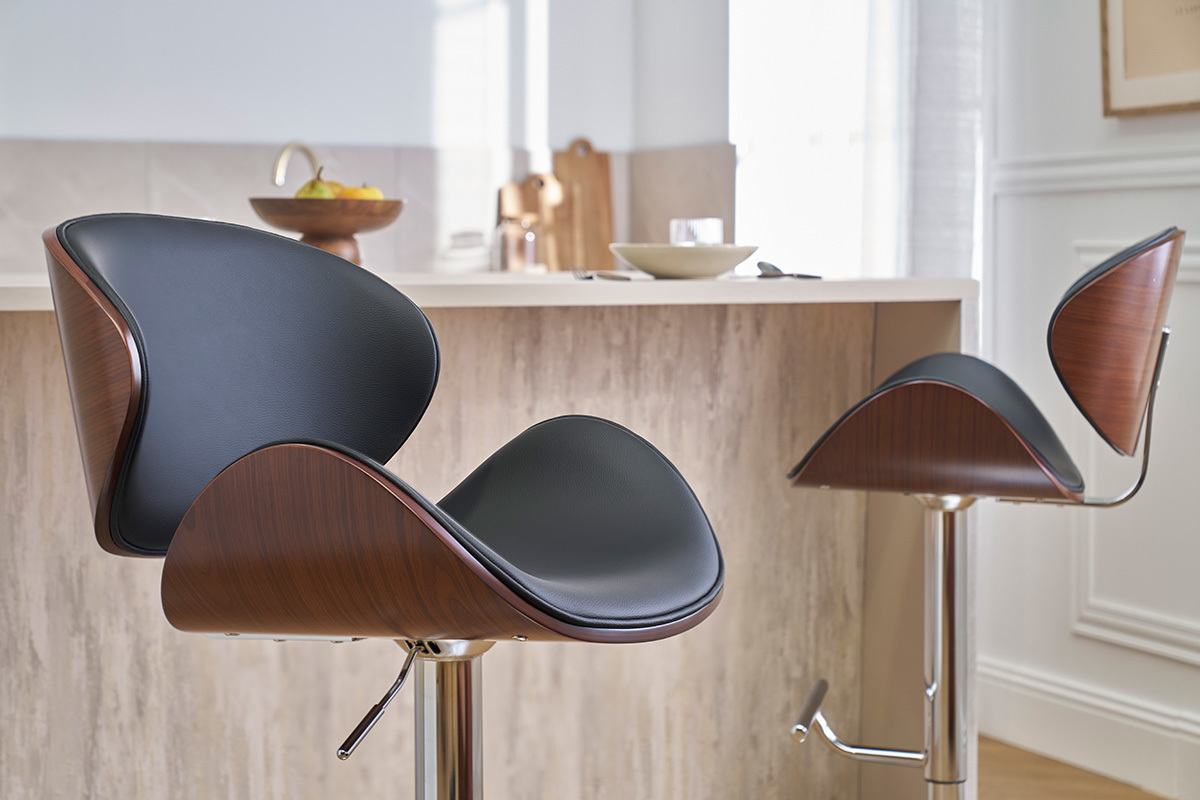 Zwei schwarze Barhocker, dunkles Holz und verchromtes Metall, vor einer Kchentheke.