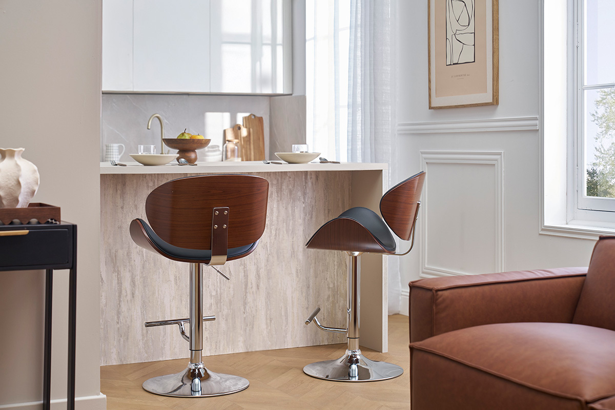 Zwei schwarze und dunkelbraune Barhocker vor einer Theke, Rckansicht.