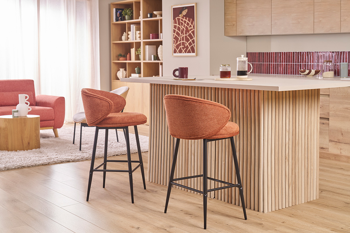 Barhocker aus verbranntem Stoff und schwarzem Metall vor einer K�cheninsel aus Holz.