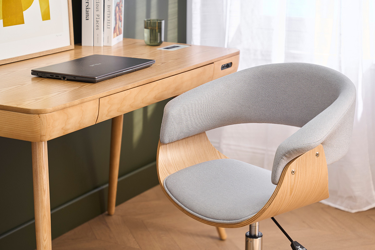 Grauer B�rostuhl mit Rollen vor einem hellen Holzschreibtisch, Seitenansicht.