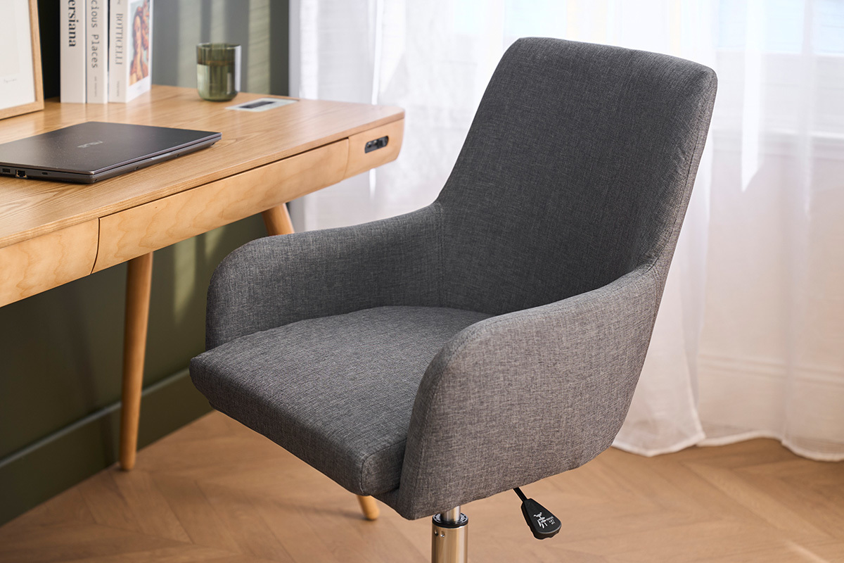 B�rostuhl aus grauem Stoff, 3/4 Ansicht, mit Armlehnen vor einem Holzschreibtisch.