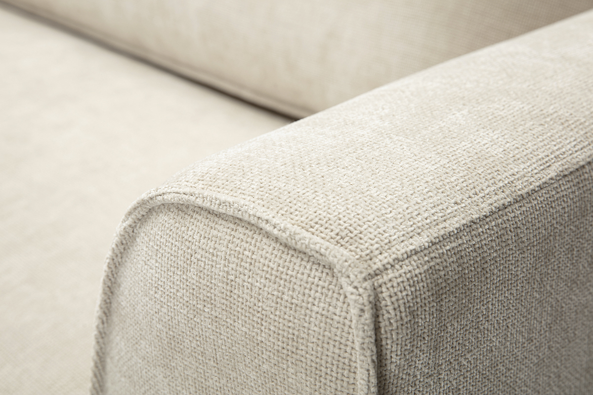 Nahaufnahme der Armlehne eines Sofas aus beigem texturiertem Samtstoff.