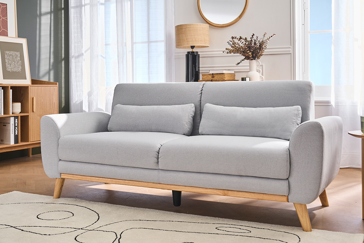 Skandinavisches Sofa f�r 3 Personen, hellgrauer Stoff, helle Holzf��e, Ansicht im 3/4-Winkel in einem Wohnzimmer.