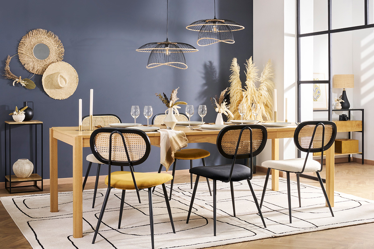 Designersessel aus Samt und Rattan um einen Tisch aus hellem Holz.