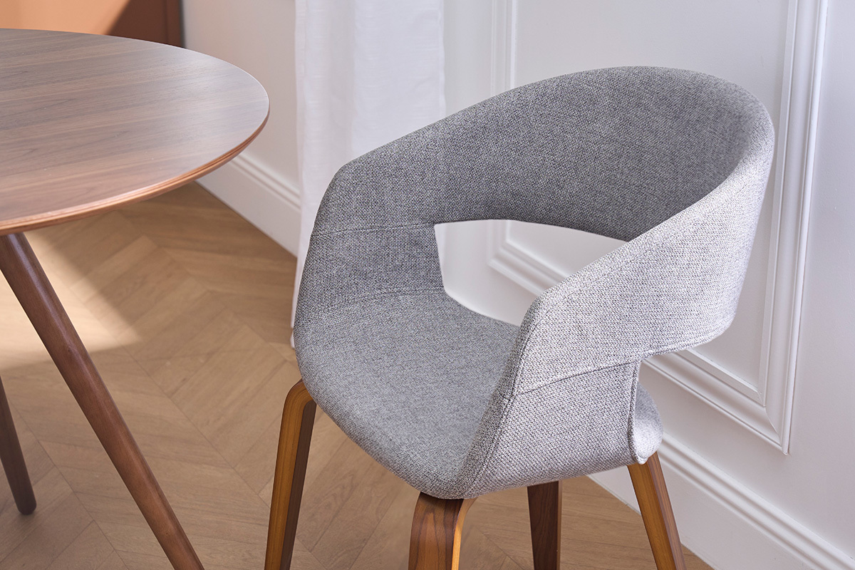Designstuhl aus grauem Stoff mit dunklen Holzbeinen, Nahaufnahme.