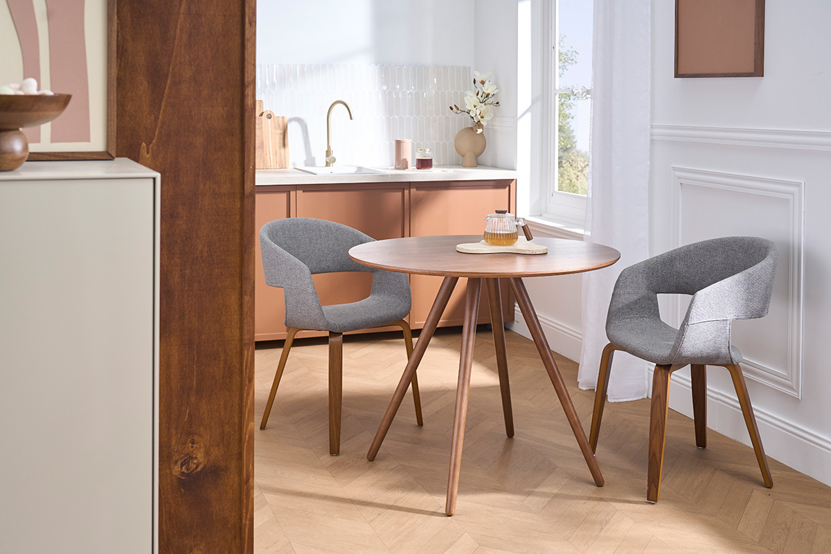 Graue Designst�hle aus Stoff mit dunklen Holzbeinen um einen runden Tisch in einem modernen Innenraum.