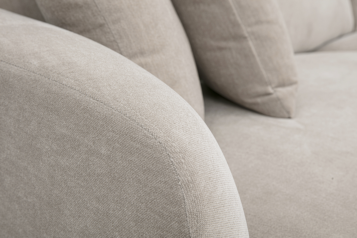 Detail des 3-Sitzer-Designsofas aus taupefarbenem Stoff mit abgerundeten Armlehnen und weichen Kissen.