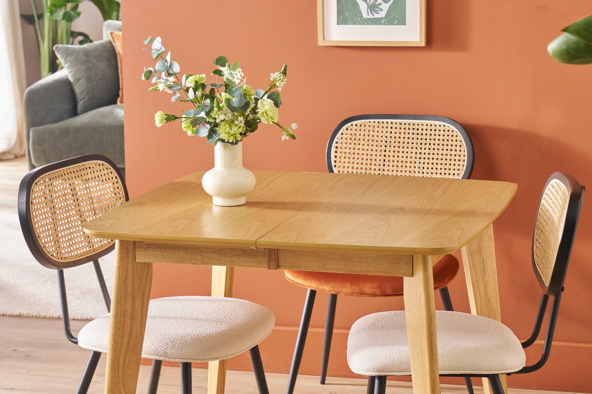 Zwei SWANN St�hle aus wei�em Stoff und Rattan um einen Tisch aus hellem Holz, Vase mit Blumen.