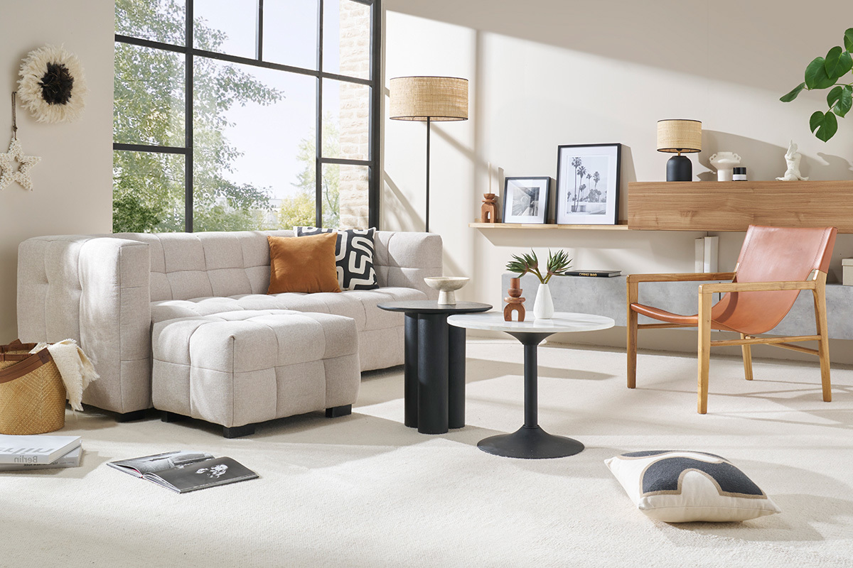 Wohnzimmer mit beigem Stoffsofa, Stehlampe, Couchtisch und Ledersessel.