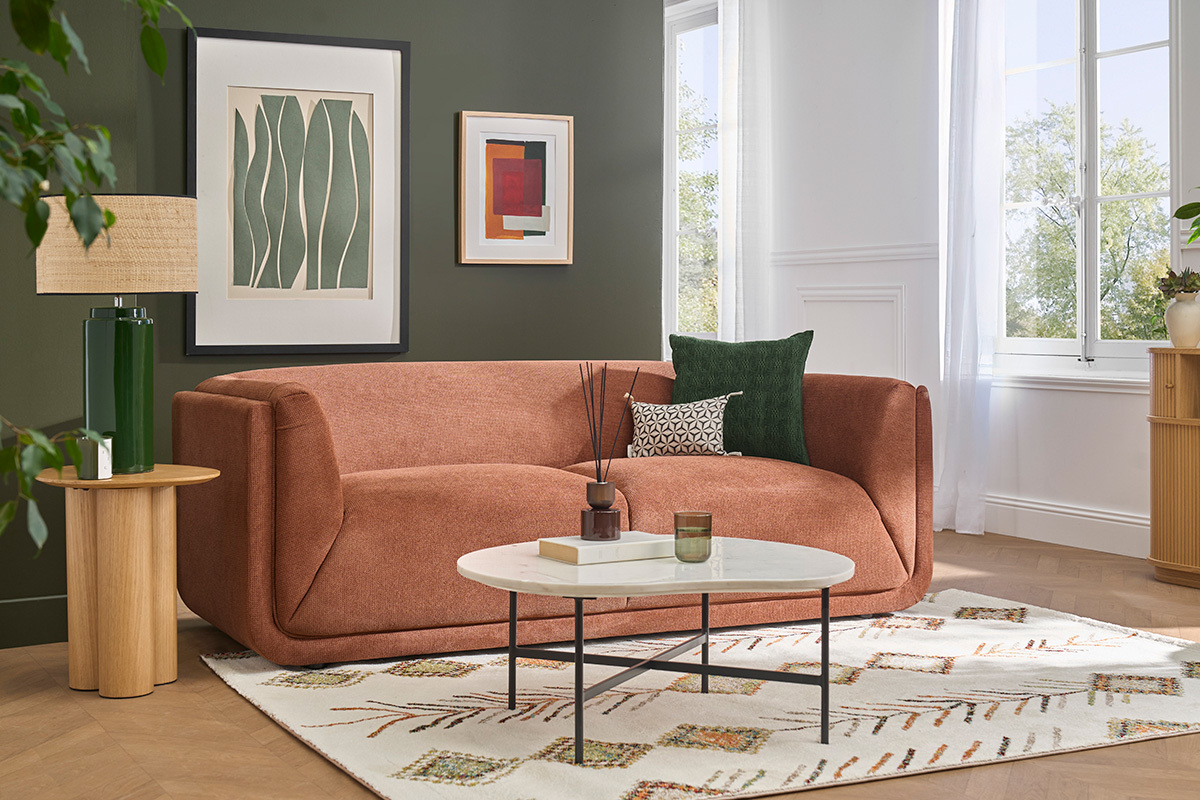 3-Sitzer Sofa HOSBO in verbranntem Erde Chenille-Stoff in einem modernen Wohnzimmer mit Couchtisch und Teppich.