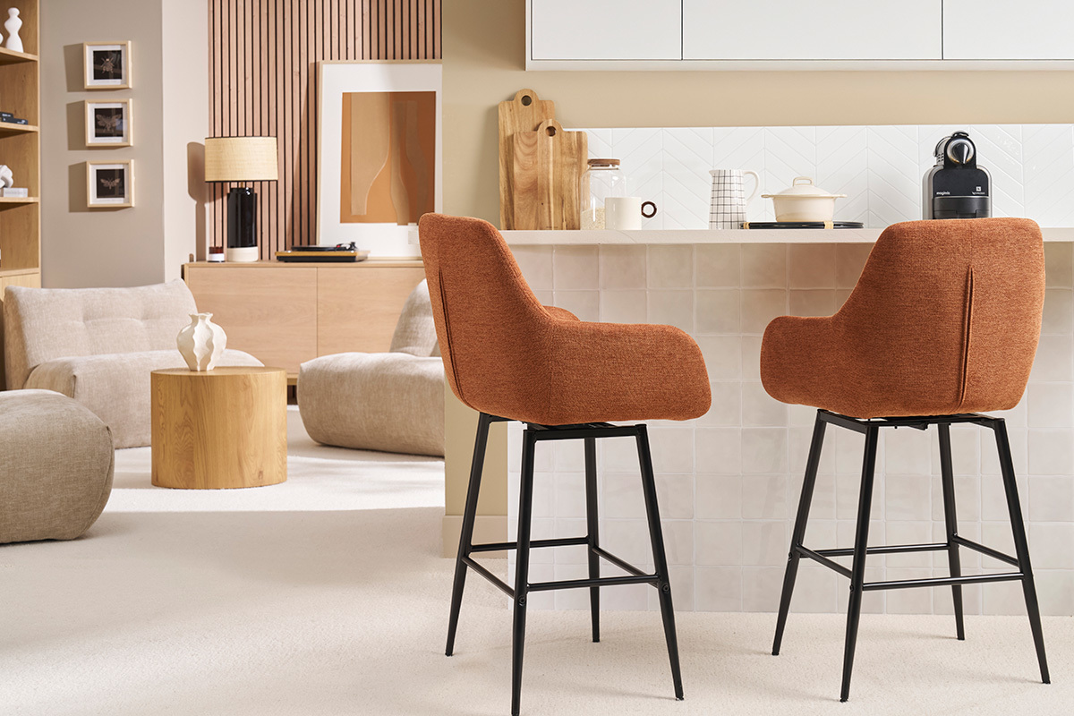 Zwei Barhocker aus verbranntem Stoff und schwarzem Metall vor einer Theke.