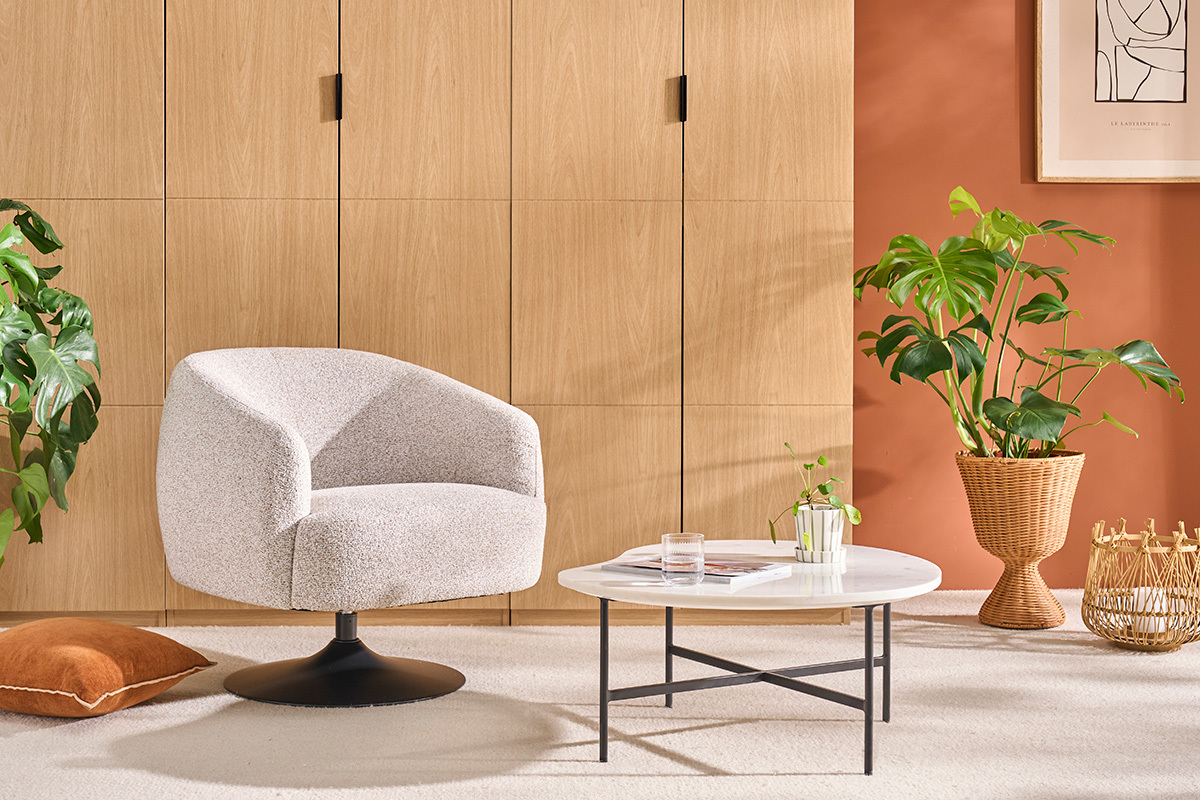 BOWIE Sessel in gebrannter Erde Chenille-Effekt Stoff, 3/4 Ansicht mit Couchtisch und Pflanze.