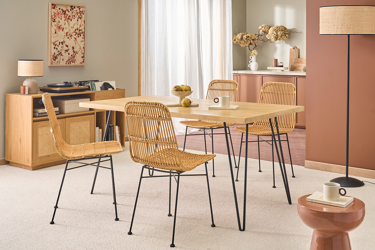 Holz-Esstisch mit schwarzen Metallbeinen, umgeben von Rattanst�hlen, Dreiviertelansicht.