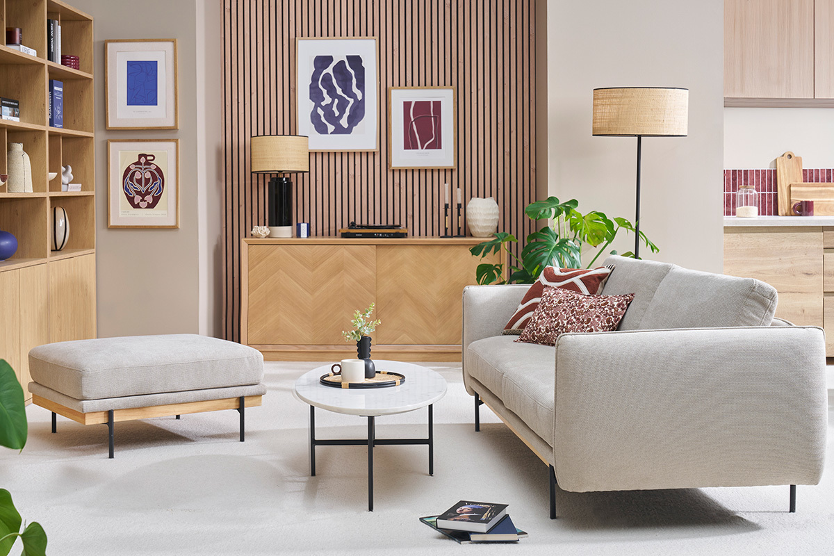 Wohnzimmer mit beigem Chenille-Stoff Fu�hocker, runder Couchtisch und Sofa.