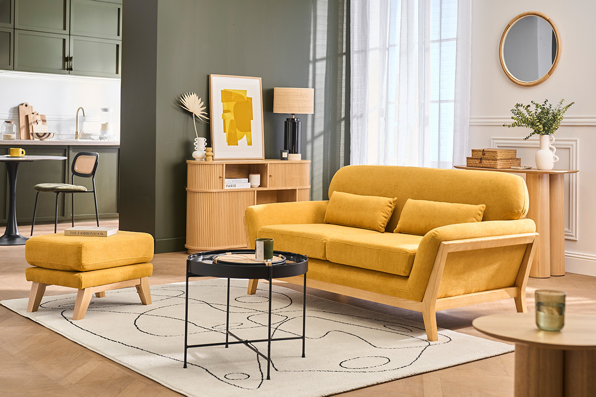 Wohnzimmer mit senfgelbem Samtstoff-Pouf, Sofa und Couchtisch.