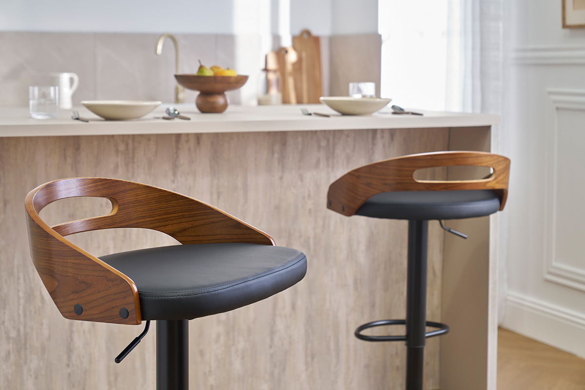 Zwei MANO Barhocker aus Walnussholz und schwarzem Leder vor einer K�chenbar.