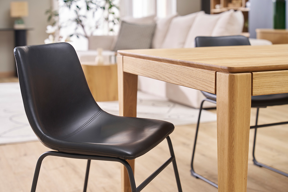 Schwarzer Industriestuhl NEW ROCK vor einem Holztisch in einem modernen Interieur.