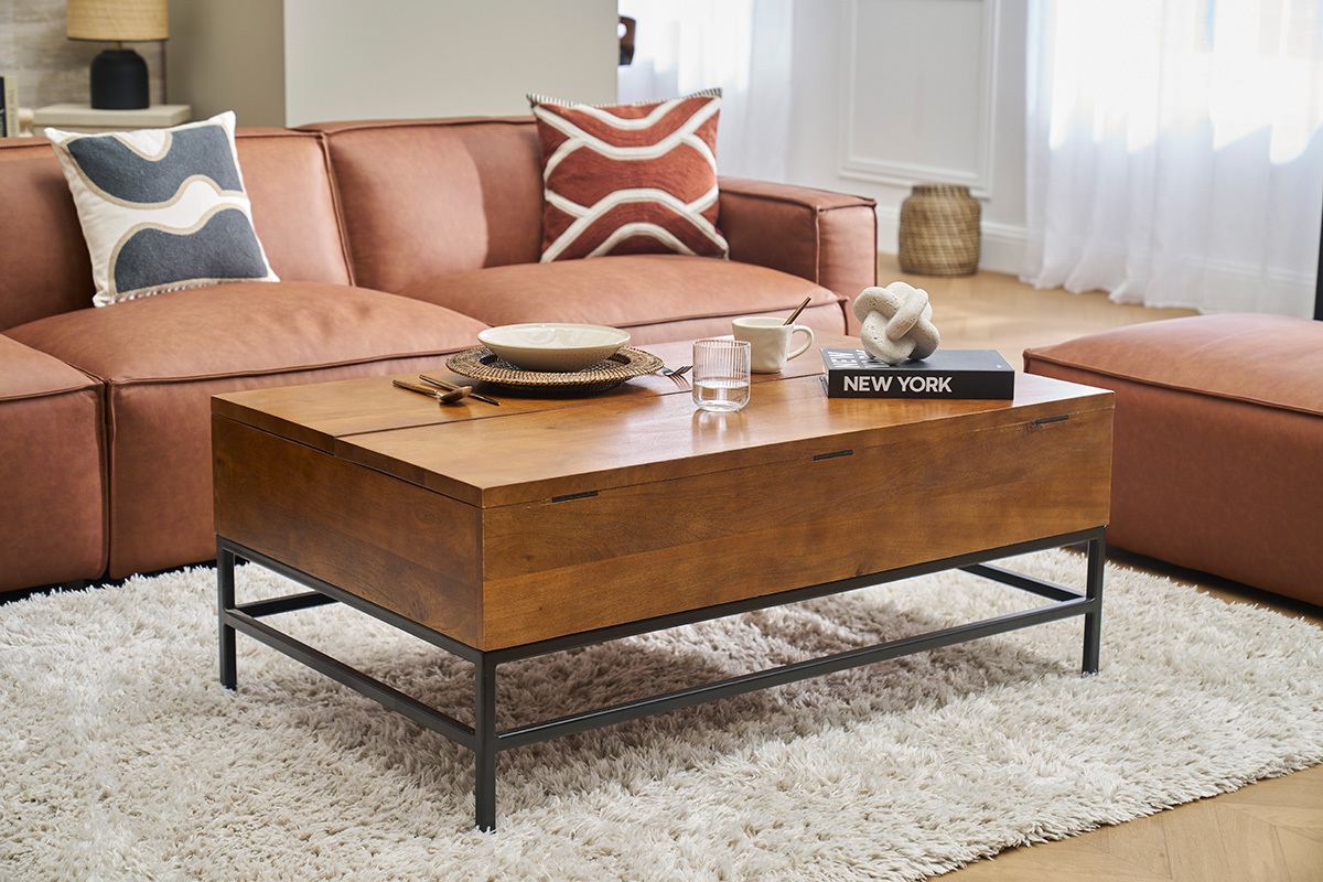 Industrieller Couchtisch aus Holz und Metall, vor einem braunen Sofa, 3/4 Ansicht, in einem Wohnzimmer.