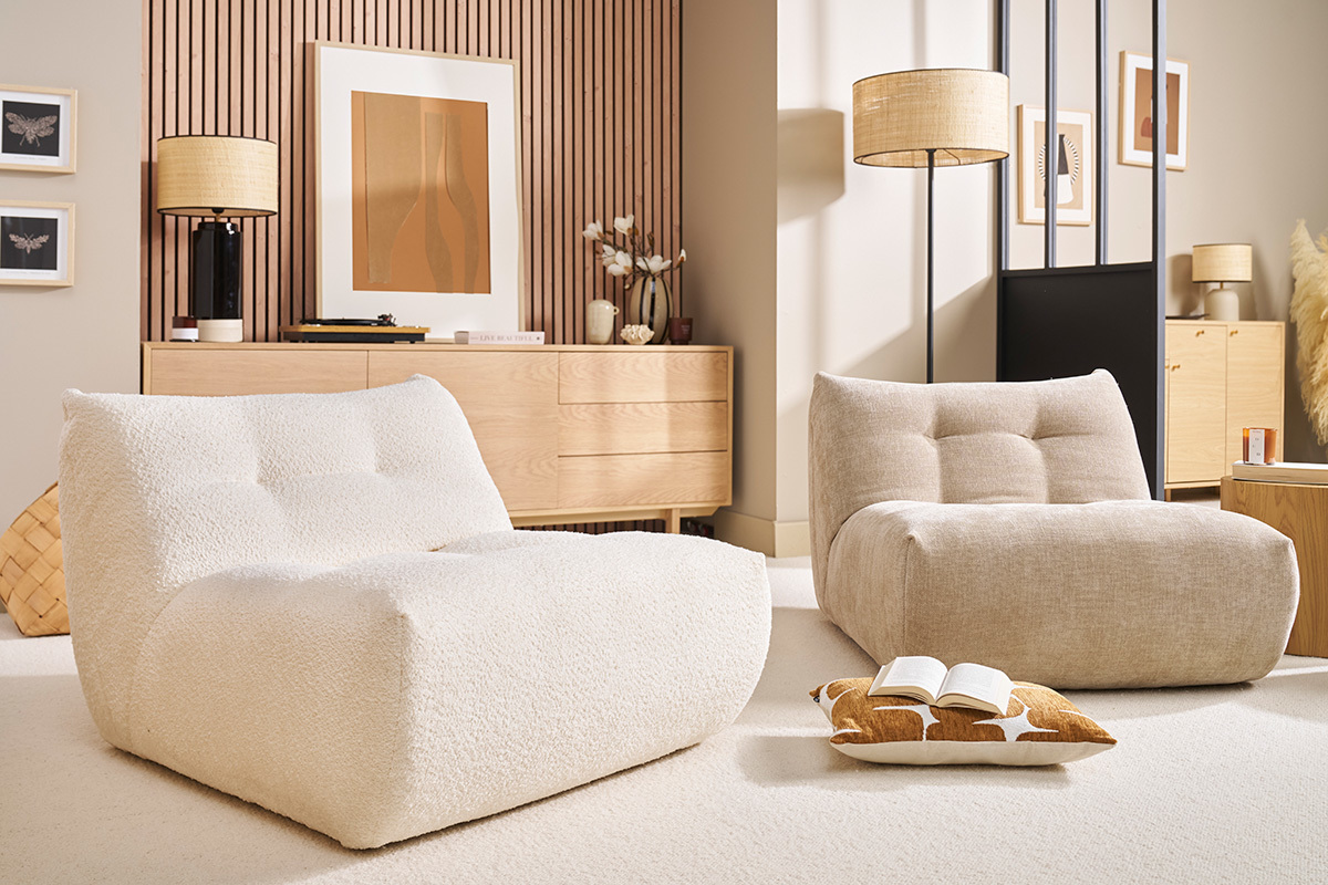 Zwei Lounge-Sessel aus hellem Stoff in einem modernen Wohnzimmer, Seitenansicht.