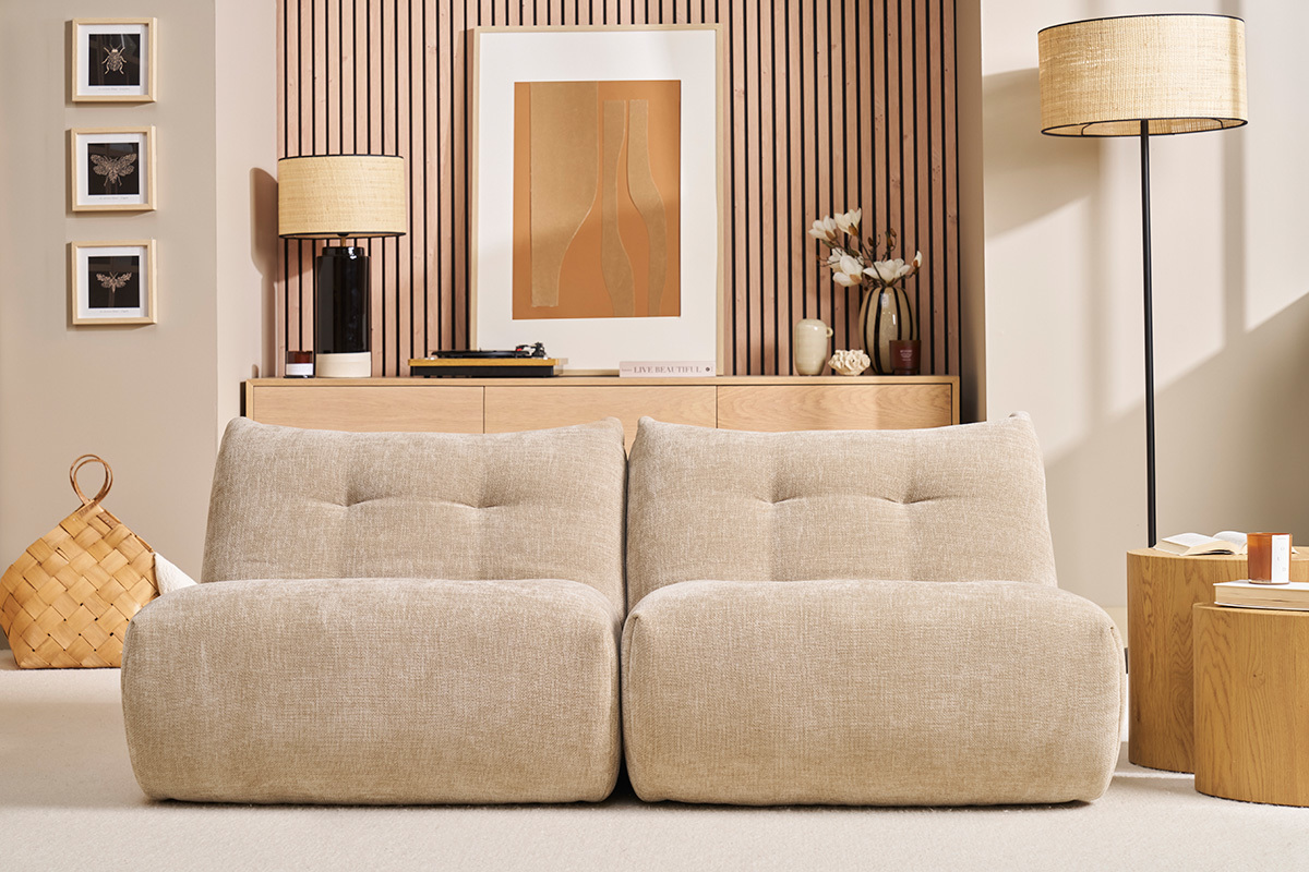 Wohnzimmer mit zwei BUMPY Lounge-Sesseln aus taupefarbenem Samt vor einem Holzmbel.