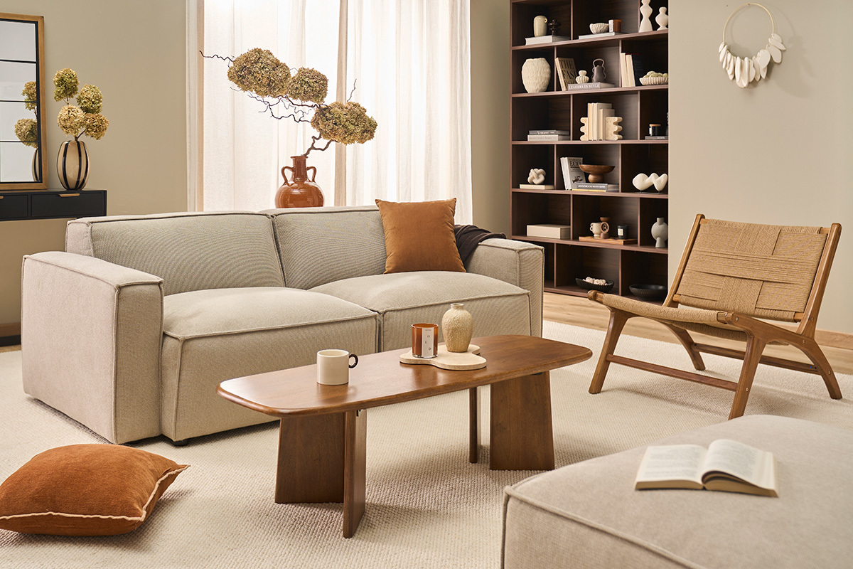 Wohnzimmer mit YARI Sessel aus Teakholz und geflochtener Schnur, beigem Sofa und Holz-Couchtisch.