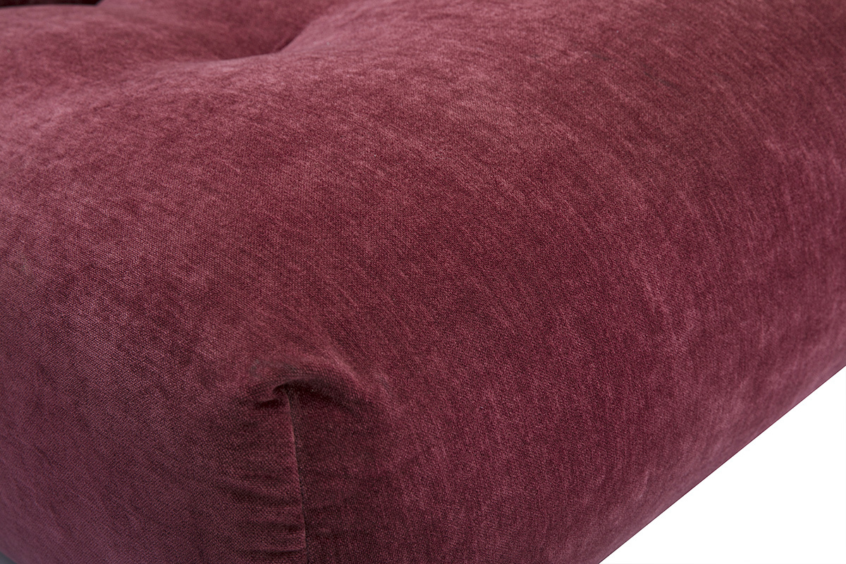 Nahaufnahme des Lounge-Sessels aus Stoff in samtiger Pflaumenoptik, die seine weiche, gesteppt wirkende Textur hervorhebt.
