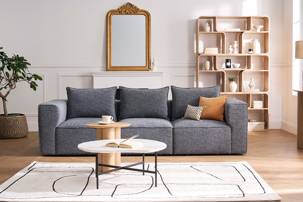 Modulares Sofa KERRY f�r 4 Personen aus grauem Stoff mit Kissen, Couchtisch und Teppich in einem zeitgen�ssischen Wohnzimmer.
