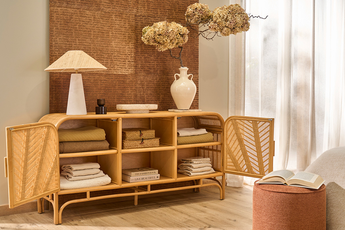 Buffet aus Rattan mit zwei offenen T�ren, Regalen, Objekten und Dekoration.