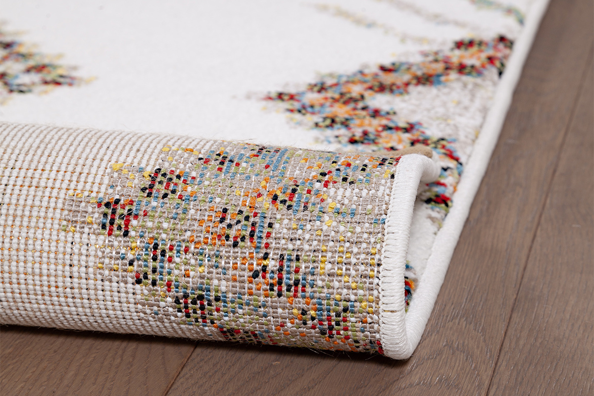 Nahaufnahme des Randes eines gemusterten Teppichs auf Parkett.