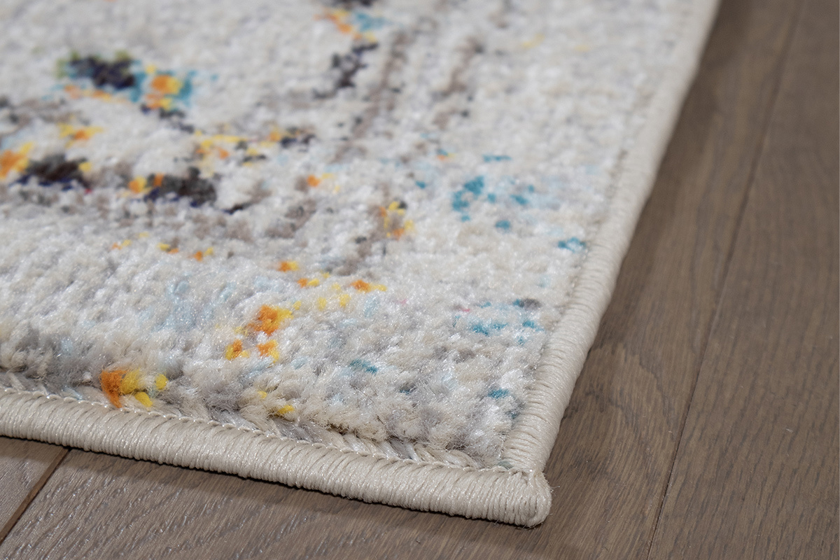 Rechteckiger Teppich DULCE in Mehrfarben, Nahaufnahme des Musters und Rand auf Holzboden.