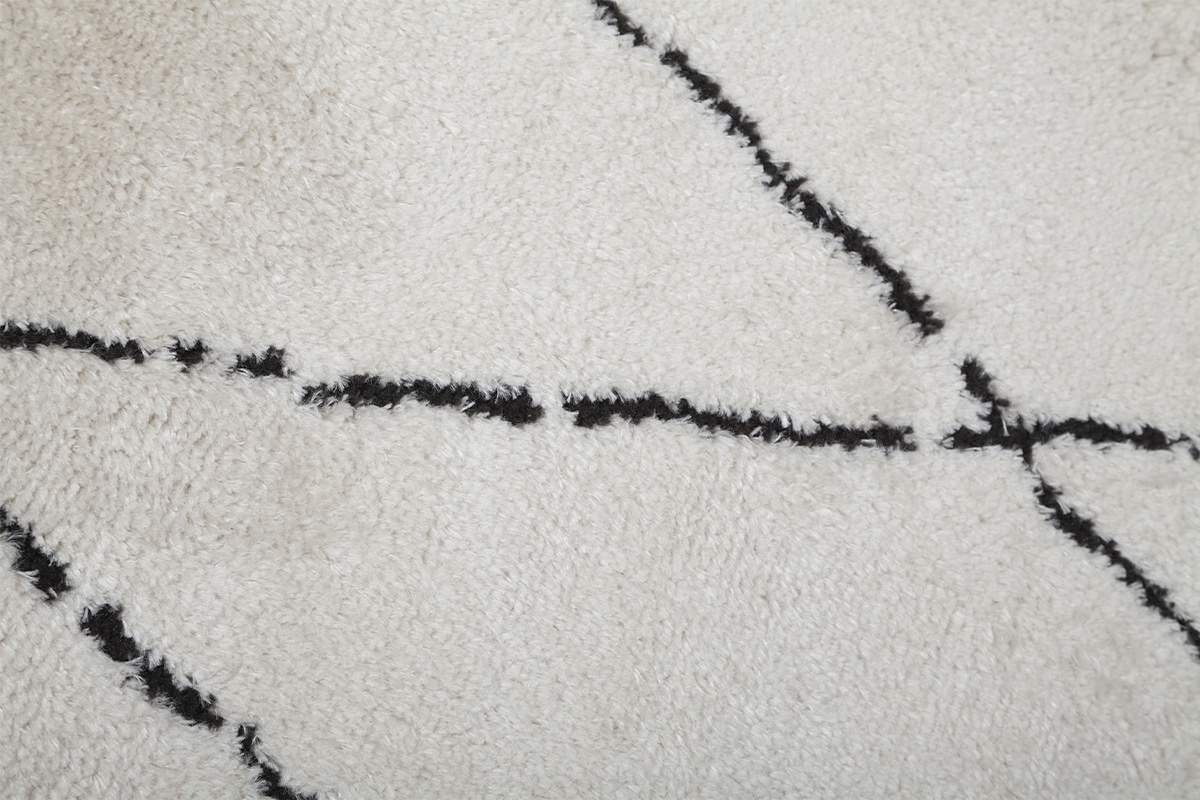 Nahaufnahme eines Teppichs mit schwarzem Diamantmuster auf gebrochen wei�em Hintergrund.