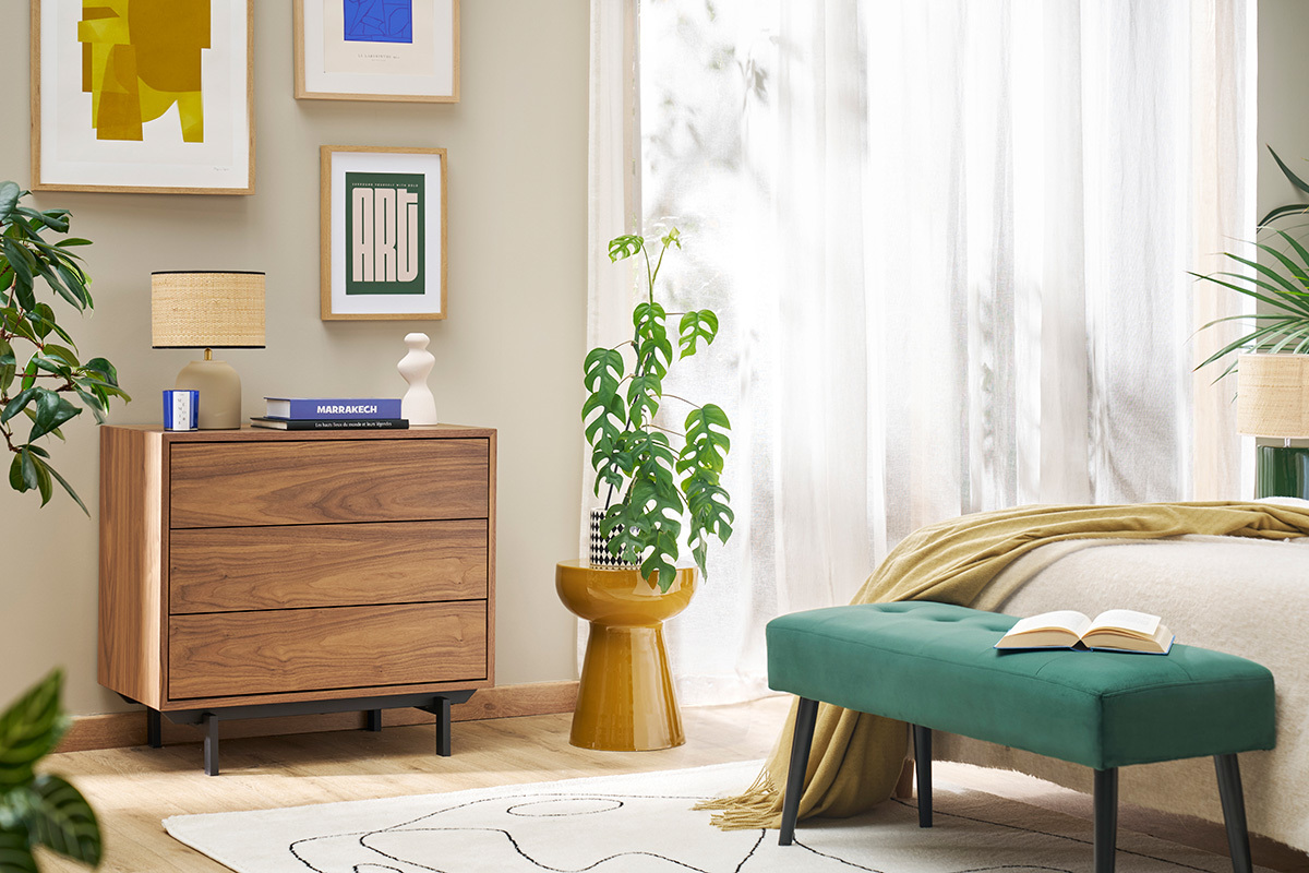 Runder Beistelltisch aus bronzefarbenem emailliertem Metall mit Pflanze, in hellem Zimmer.