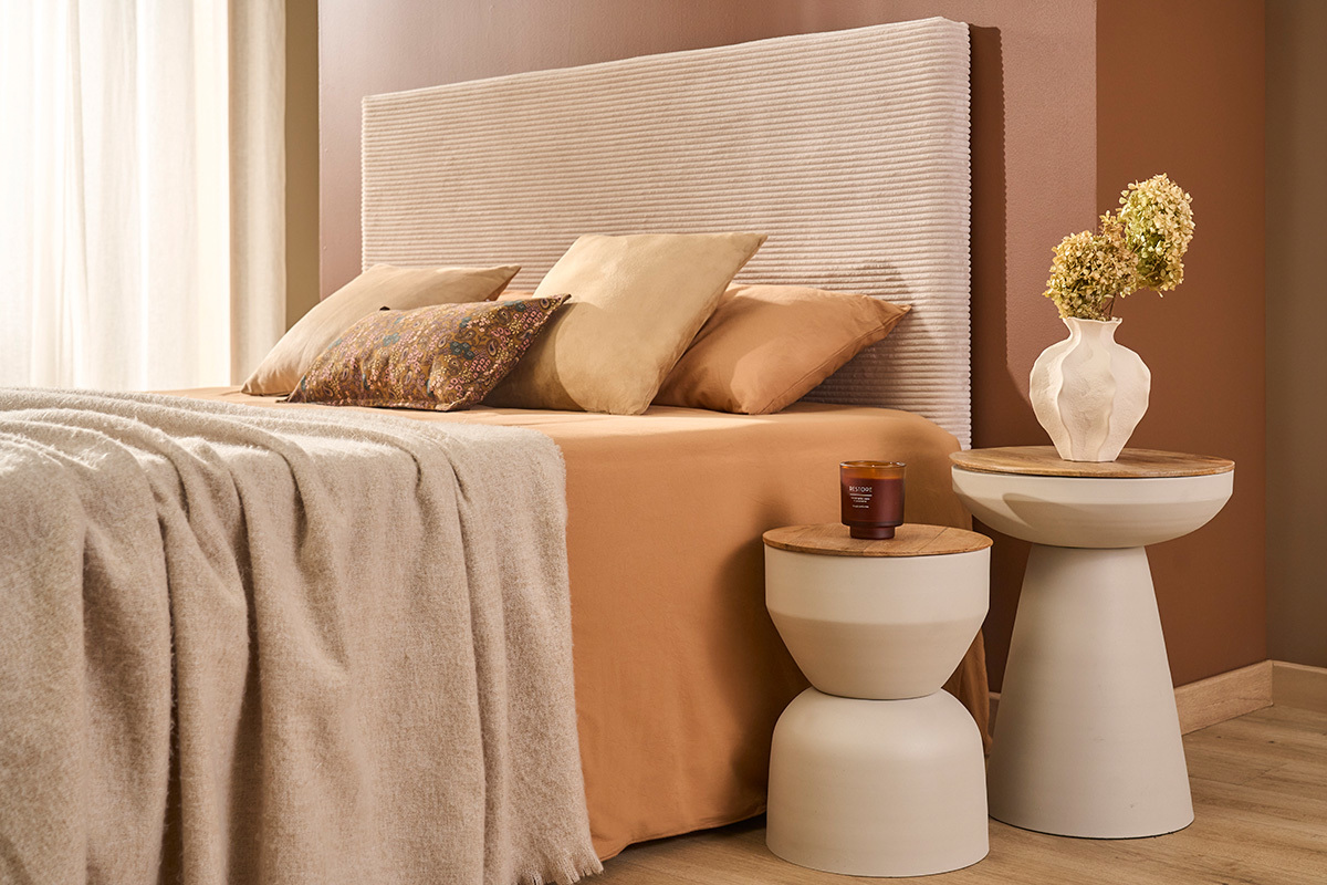 YOYO Beistelltische aus greige Metall und Mangoholz, neben einem Bett mit Dekorationen.