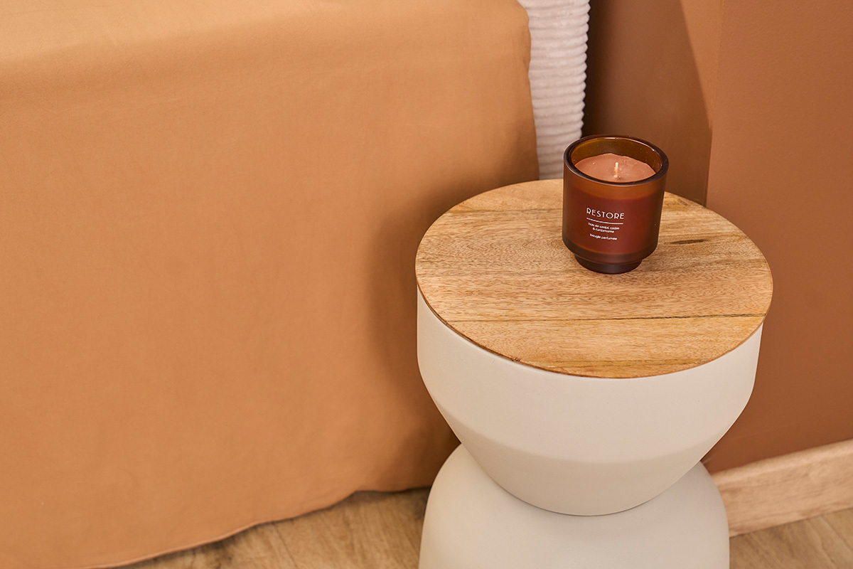 Runder Beistelltisch aus kreidigem Metall mit Holzplatte und Kerze, Draufsicht.