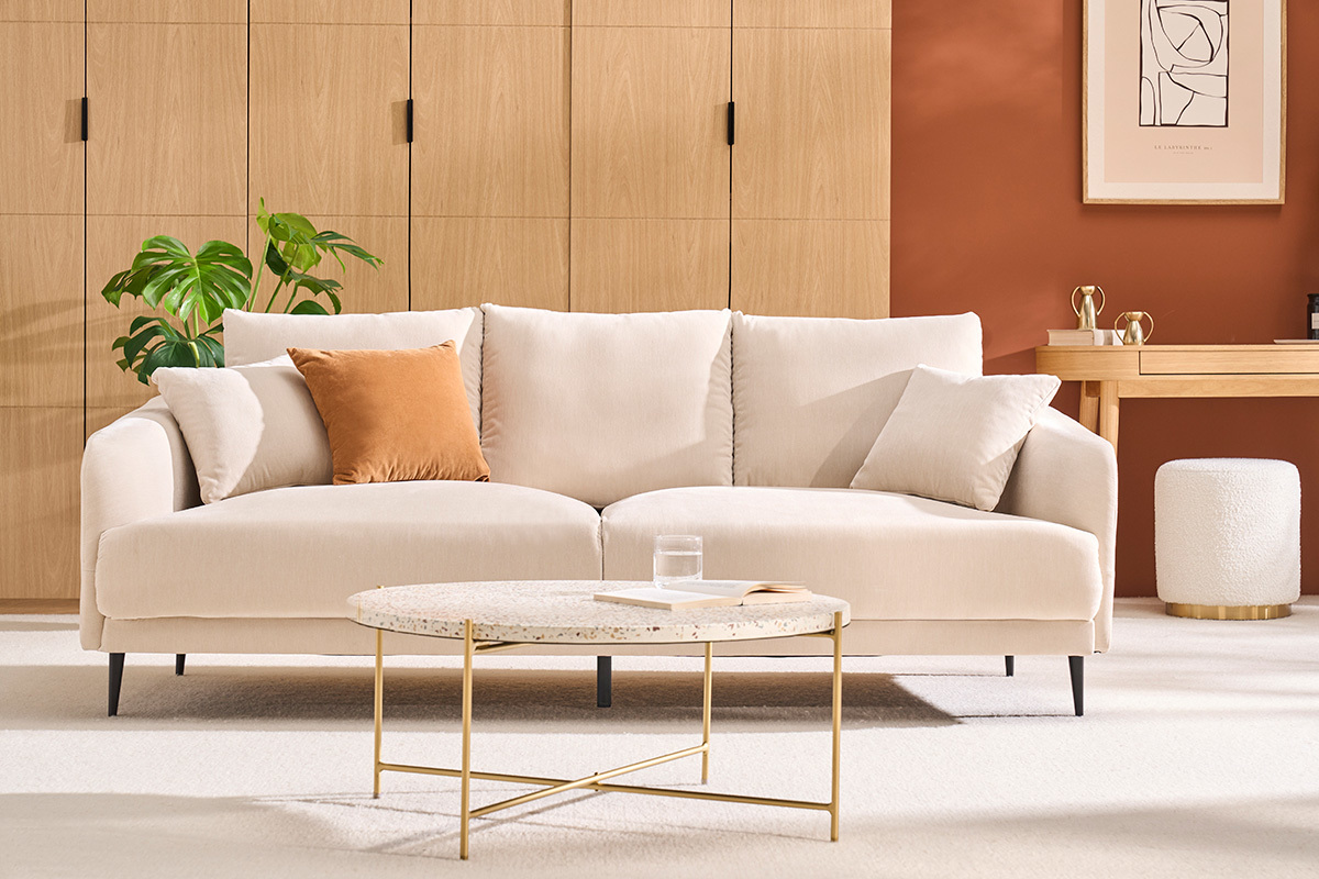 Runder Couchtisch aus Terrazzo und Metall, Frontansicht, mit Sofa und Dekoration in einem modernen Wohnzimmer.